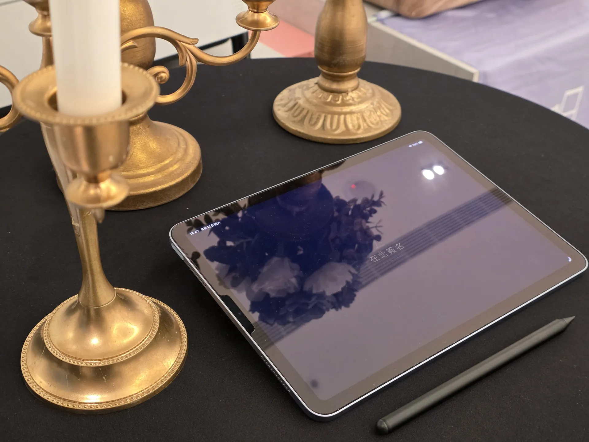 The signing tablet and its stylus on a table beside candlesticks